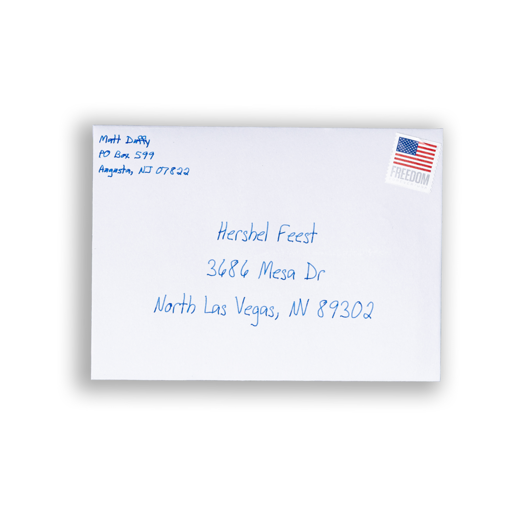 A White A6 envelope with blue handwriting on it and a stamp.