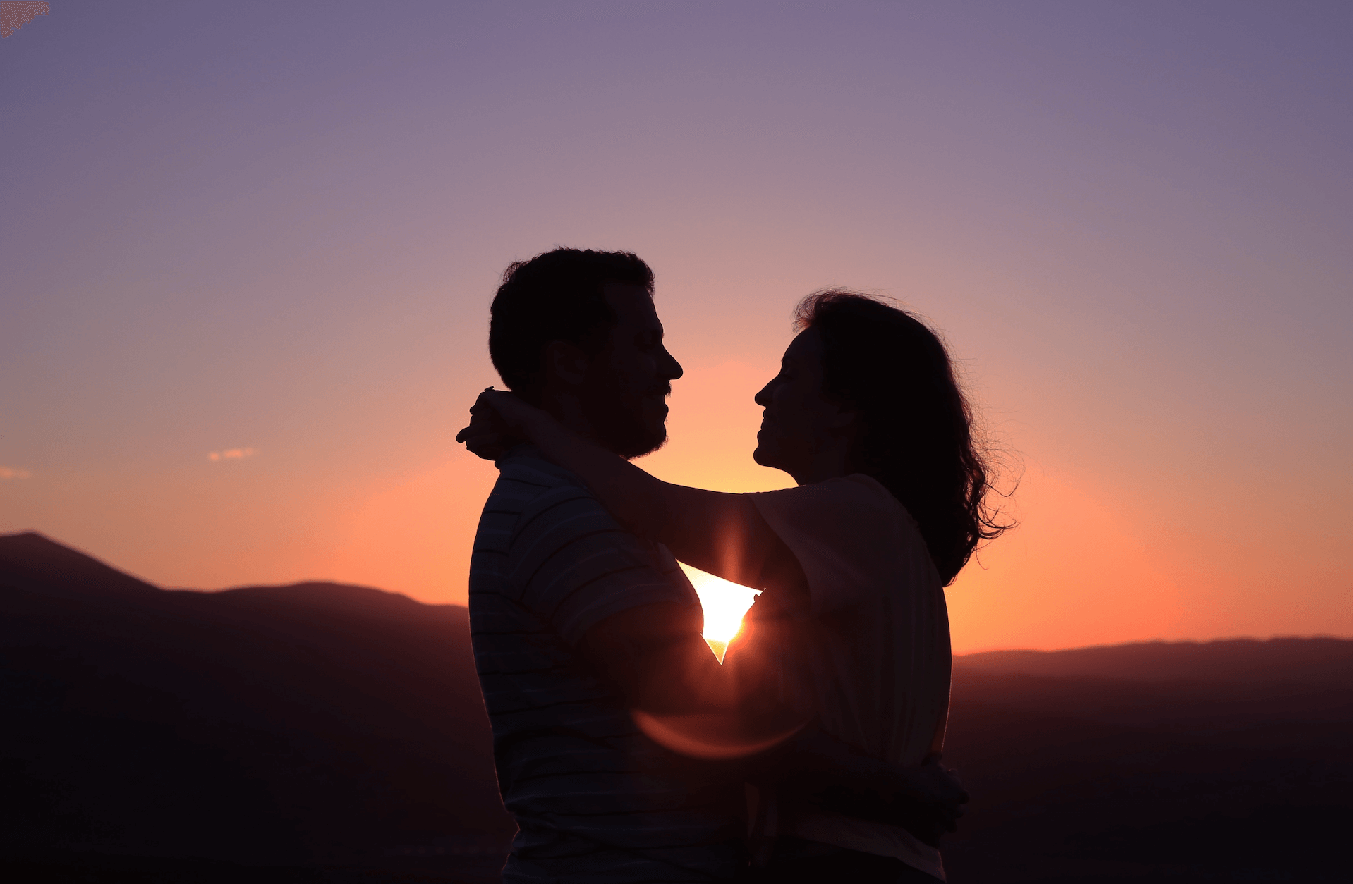 Ehepaar umarmt sich bei Sonnenuntergang.