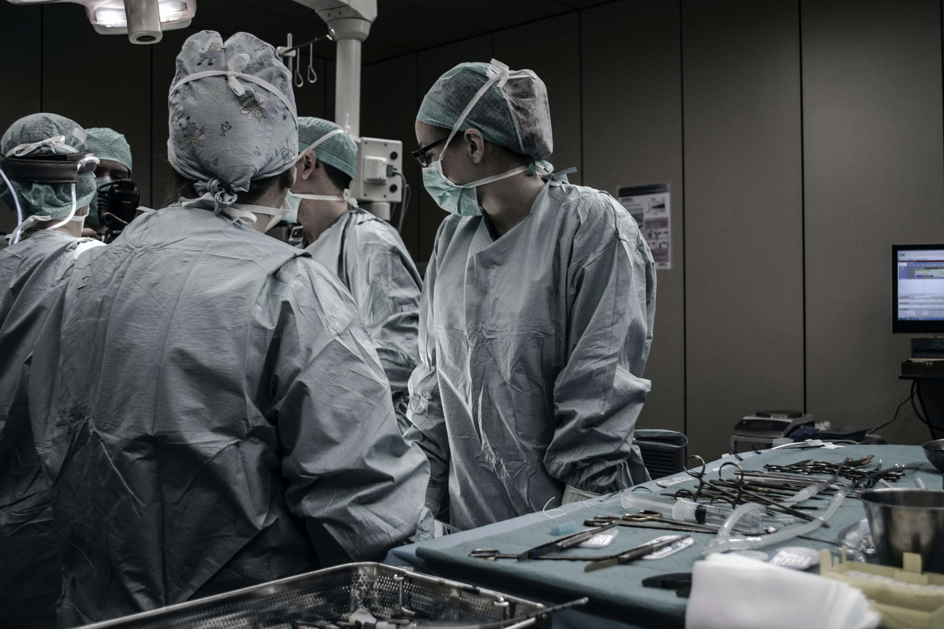 5 Chirurgen stehen im OP-Raum um einen liegenden Patienten.